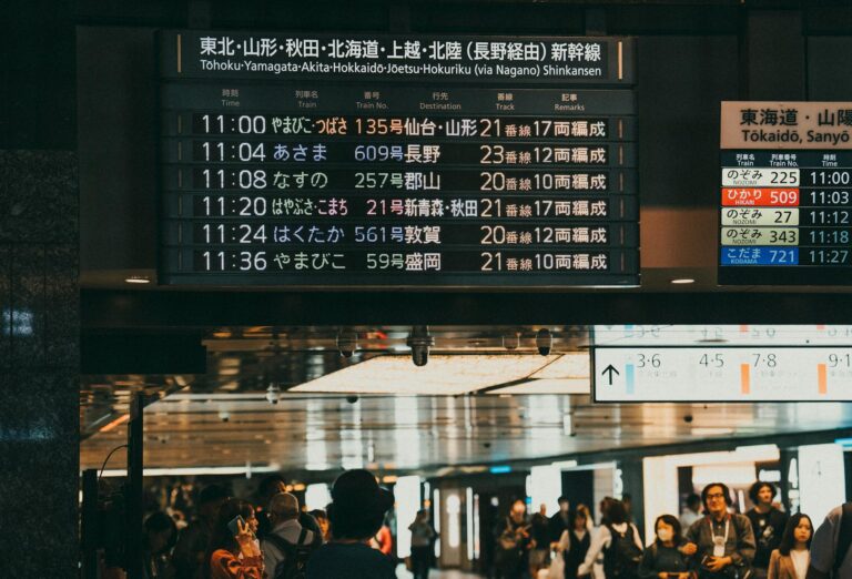 Digital departure board displaying train schedules at a busy Japanese railway station
