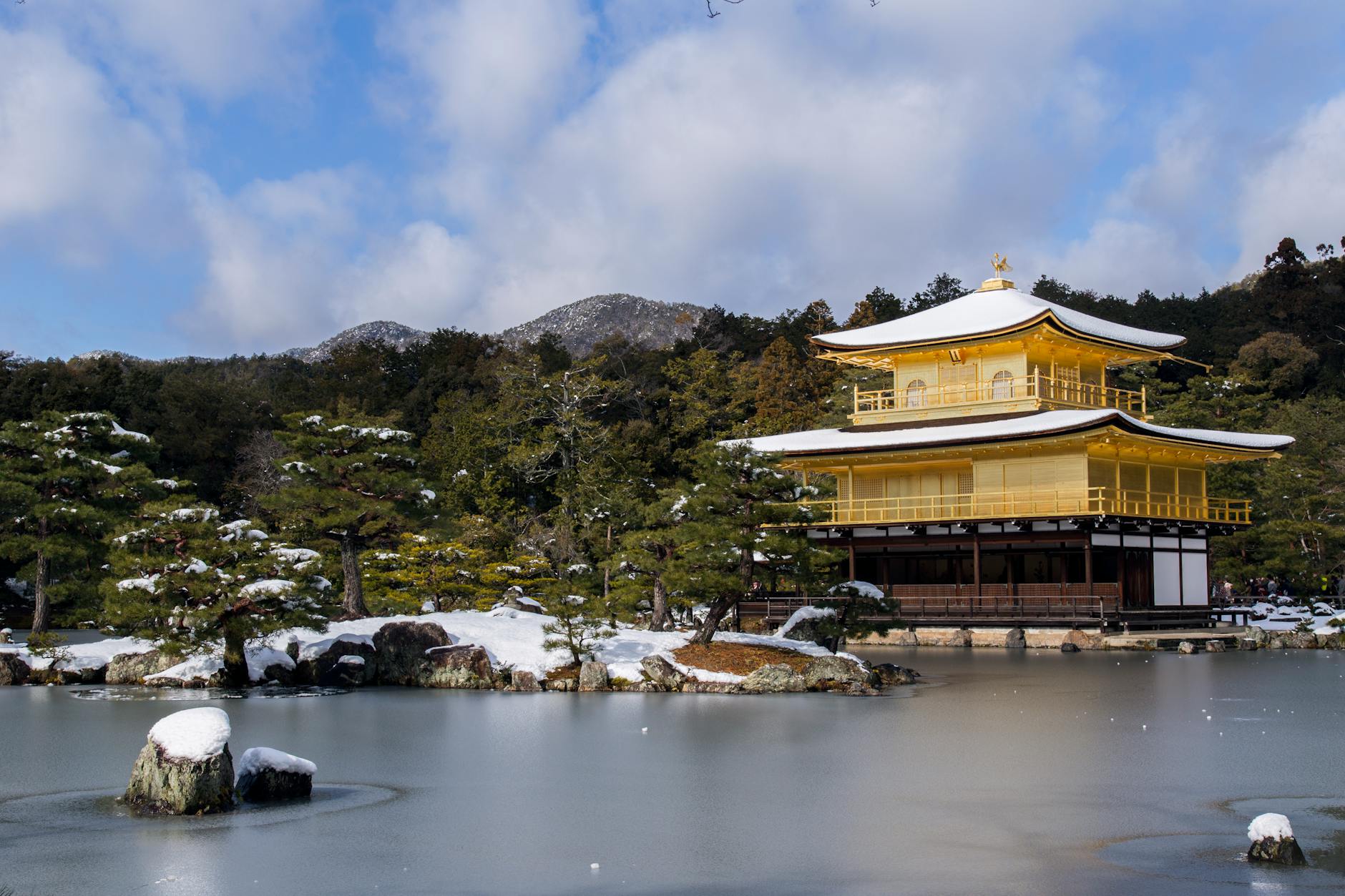 Kinkaku-ji Golden Pavilion reflected in a pond surrounded by snow-covered landscape in Kyoto, Japan