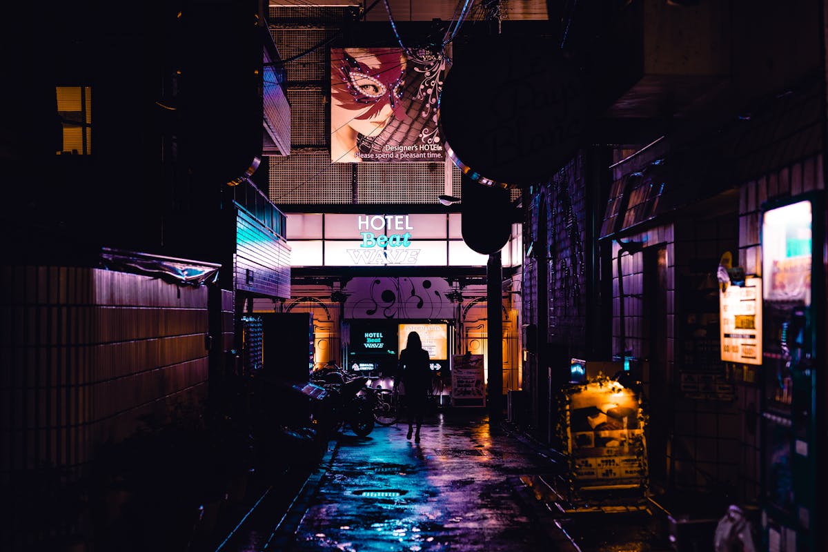 Silhouette of person walking through neon-lit alleyway in Shinjuku Tokyo at night
