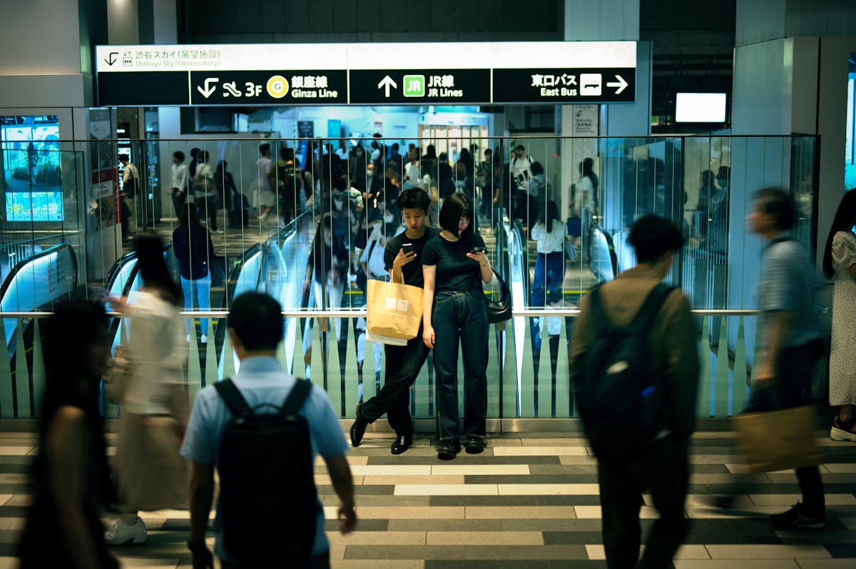 Crowded scene inside Shinjuku Station Tokyo with busy commuters escalators and signage