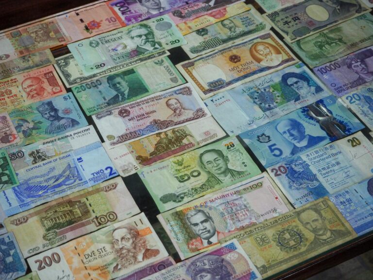 Colorful banknotes from various countries arranged on a table, representing currency exchange for travel in Japan