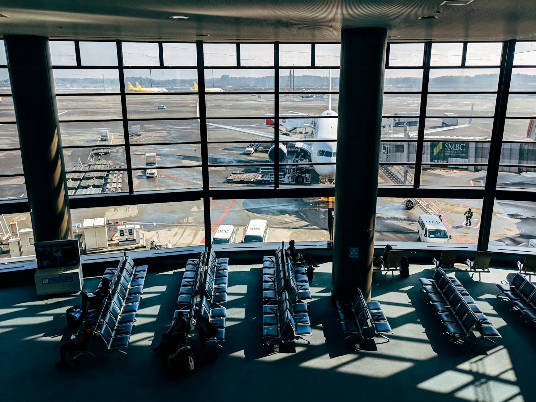 Spacious Tokyo airport terminal with view of airplane on the tarmac through glass windows