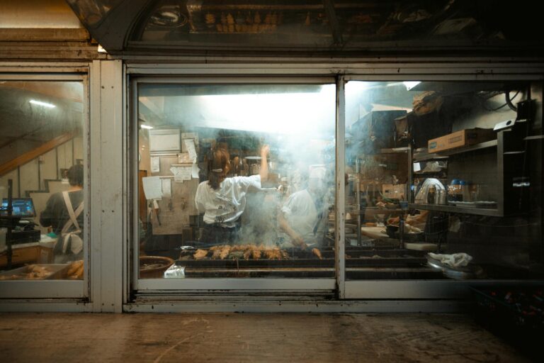 Chefs preparing food in a smoky kitchen at a Tokyo street food restaurant in Japan